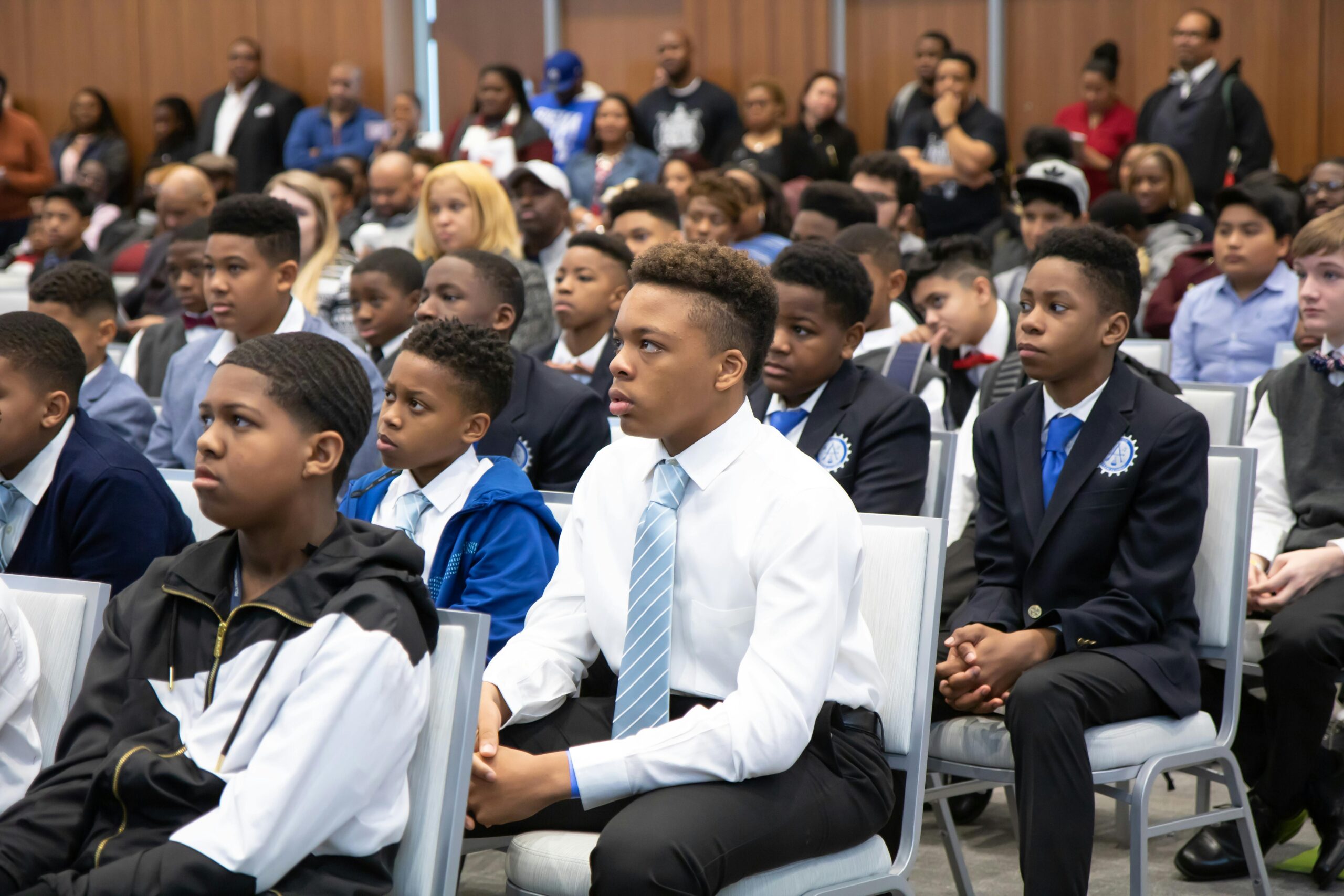 Group of young students attentively listening during an indoor educational event.