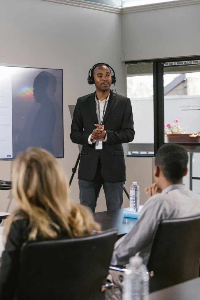 pexels-photo-7648232-7648232 A professional delivers a presentation to a diverse audience in a conference room.