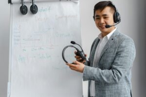 Asian man explaining a concept in a training session with a headset and flip chart.